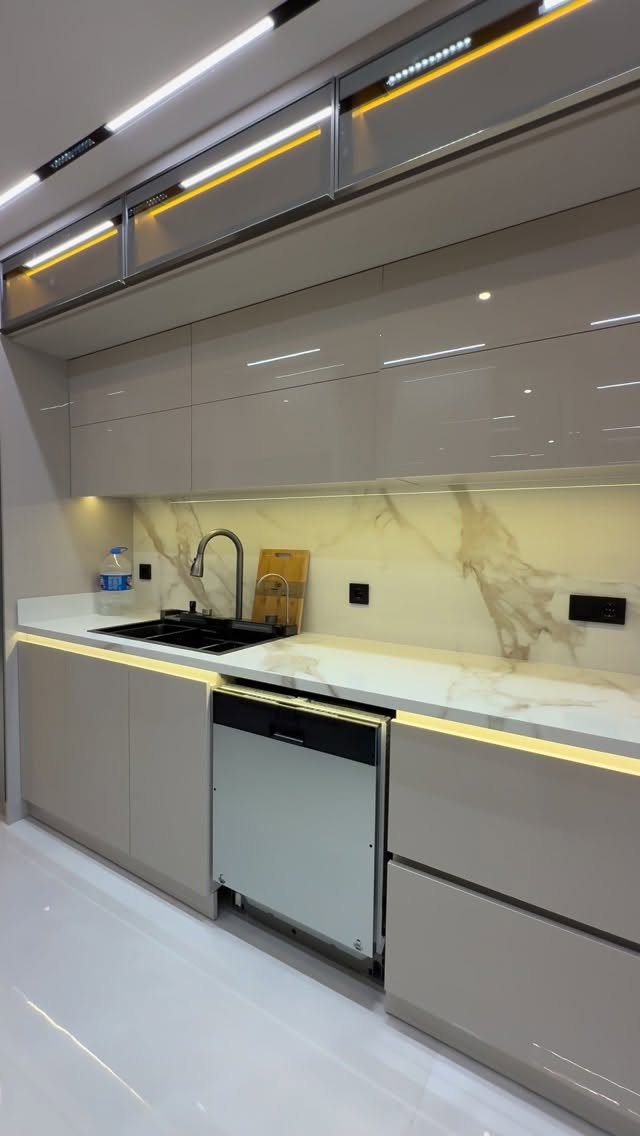 Modern kitchen with grey cabinets, white marble countertops, and a matching marble slab backsplash.