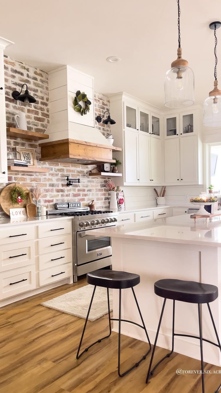A bright kitchen with white cabinets and a weathered white-washed brick backsplash.
